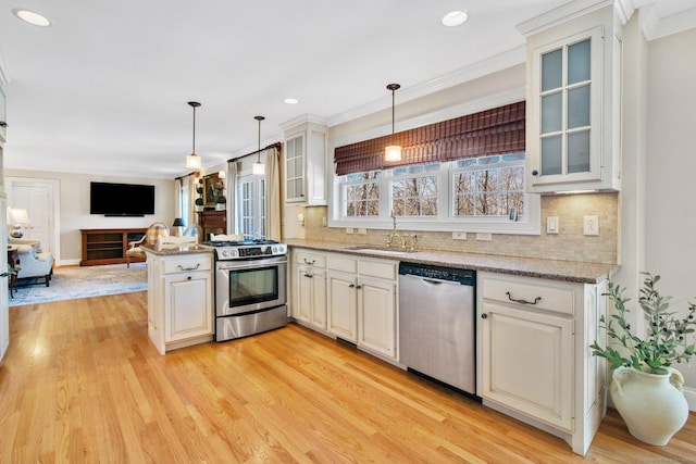 kitchen with sink, stainless steel appliances, kitchen peninsula, pendant lighting, and light wood-type flooring