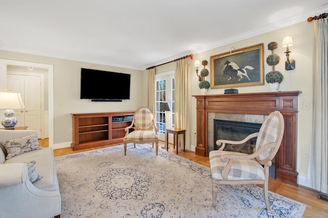 living room with a tile fireplace, light hardwood / wood-style flooring, and crown molding