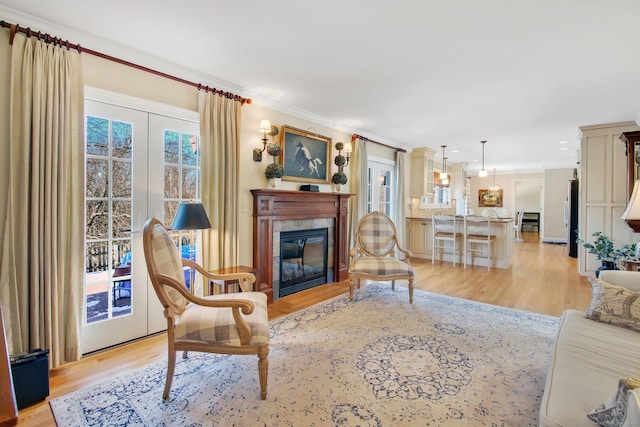 living room featuring a tile fireplace, light wood-type flooring, and crown molding