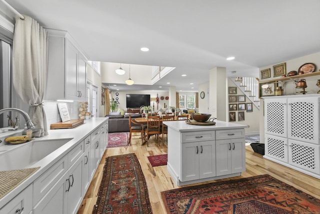 kitchen featuring white cabinets, decorative backsplash, a center island, and light hardwood / wood-style flooring