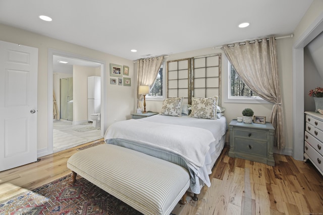 bedroom featuring light wood-type flooring, connected bathroom, and multiple windows