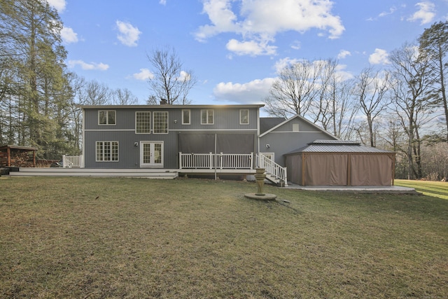 back of property with a lawn, a wooden deck, and french doors