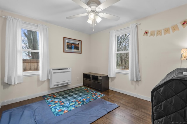 bedroom featuring ceiling fan, dark hardwood / wood-style flooring, multiple windows, and heating unit