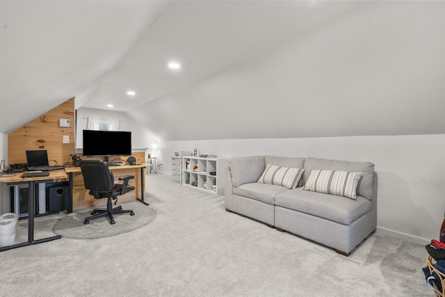 carpeted home office with wooden walls and vaulted ceiling