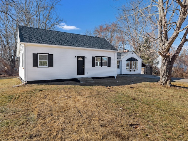 view of front facade featuring entry steps, a front lawn, and roof with shingles