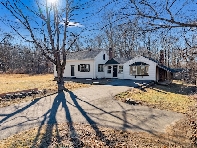 view of front of property featuring driveway, a chimney, and a front yard