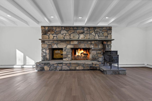 unfurnished living room with a stone fireplace, beam ceiling, a wood stove, and wood finished floors