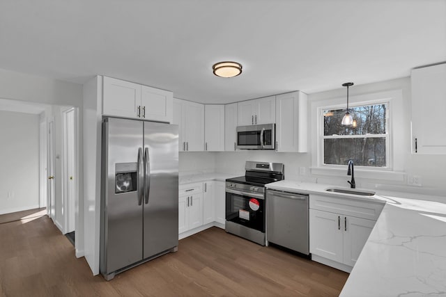 kitchen with white cabinets, a sink, stainless steel appliances, and light stone countertops