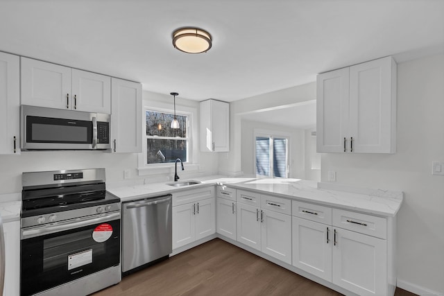 kitchen featuring white cabinets, light stone countertops, appliances with stainless steel finishes, dark wood-type flooring, and a sink