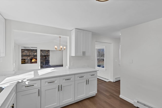 kitchen featuring white cabinets, a fireplace, and baseboard heating