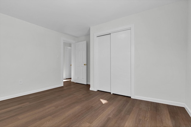 unfurnished bedroom with a closet and dark wood-type flooring