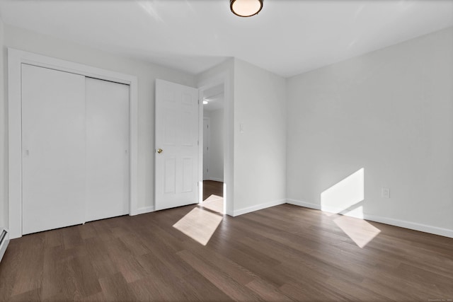 unfurnished bedroom with baseboards, wood finished floors, and a closet