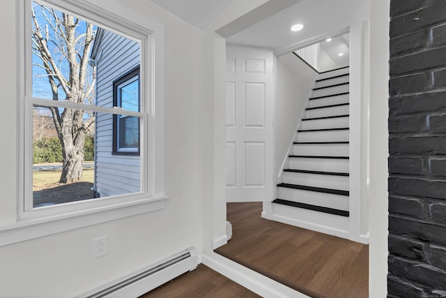 stairway with wood-type flooring and a baseboard radiator