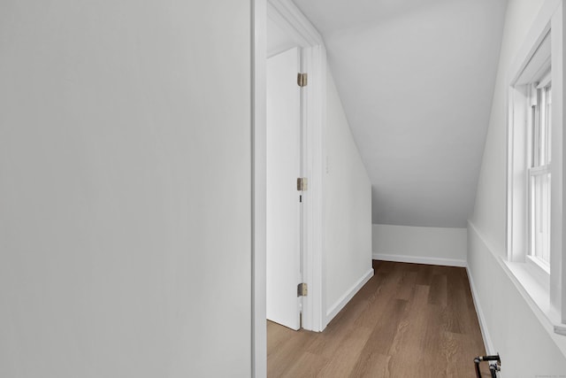 corridor featuring baseboards, lofted ceiling, and wood finished floors