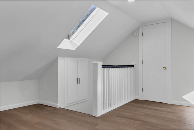 additional living space with vaulted ceiling with skylight and hardwood / wood-style flooring