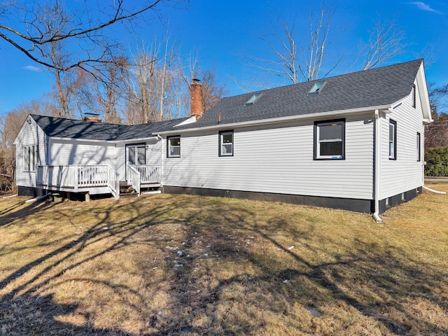rear view of house with a chimney, a deck, and a yard