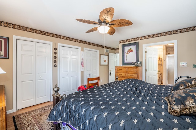 bedroom with hardwood / wood-style flooring, ceiling fan, and two closets