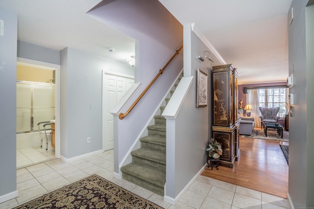 stairway with tile patterned floors and crown molding