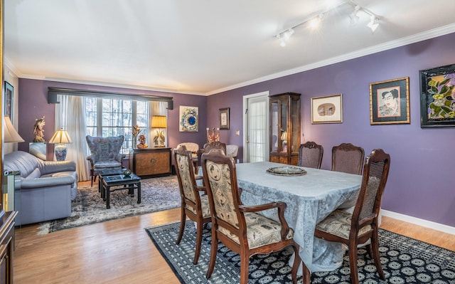 dining area with light hardwood / wood-style floors, crown molding, and rail lighting