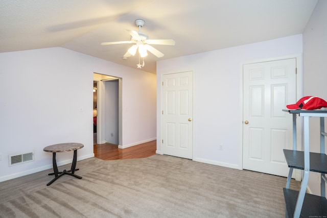 interior space featuring light carpet, ceiling fan, and vaulted ceiling