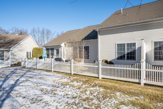 snow covered rear of property featuring a sunroom