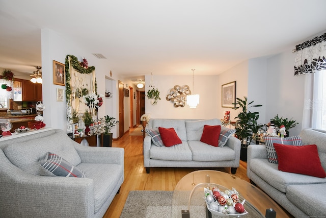 living room with light hardwood / wood-style floors and ceiling fan with notable chandelier