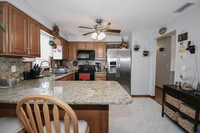 kitchen with kitchen peninsula, decorative backsplash, sink, and black appliances