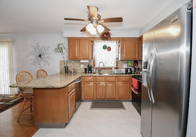 kitchen featuring kitchen peninsula, decorative backsplash, a kitchen bar, light stone countertops, and stainless steel appliances