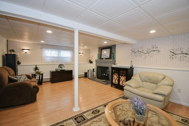 living room featuring hardwood / wood-style flooring, a baseboard heating unit, and a brick fireplace