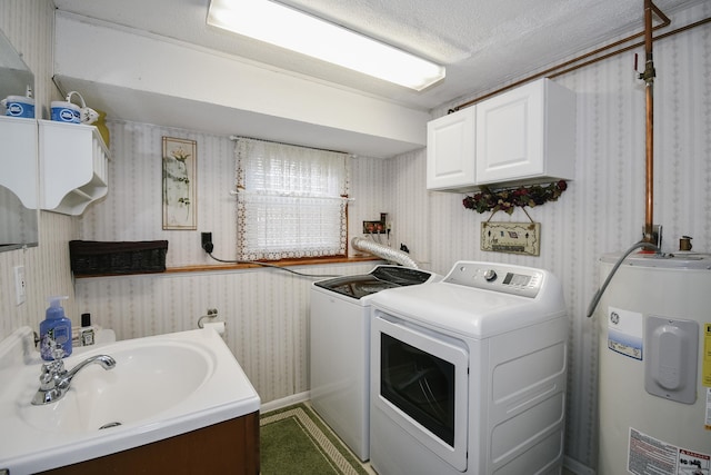 laundry room featuring cabinets, a textured ceiling, electric water heater, washer and clothes dryer, and sink