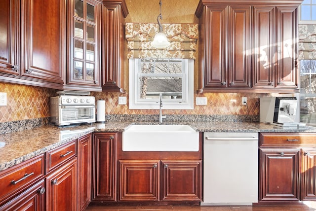 kitchen featuring dishwasher, light stone counters, sink, and decorative light fixtures