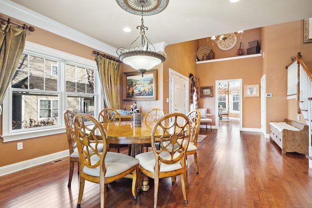 dining area with a healthy amount of sunlight, wood-type flooring, ornamental molding, and an inviting chandelier