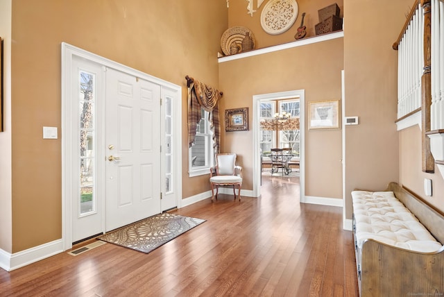 entryway featuring wood-type flooring and a towering ceiling