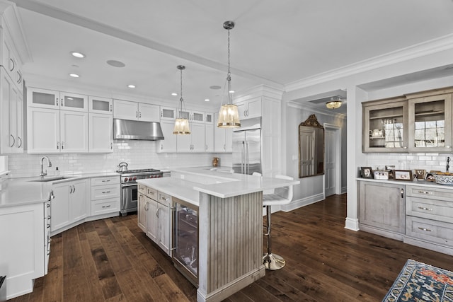 kitchen featuring glass insert cabinets, a center island, high quality appliances, and under cabinet range hood