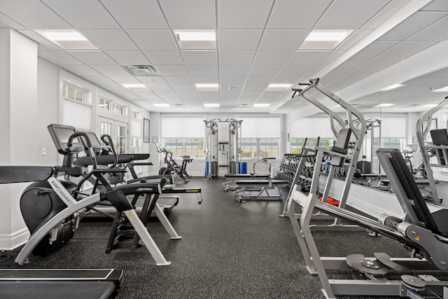 gym with a paneled ceiling, baseboards, visible vents, and a wealth of natural light