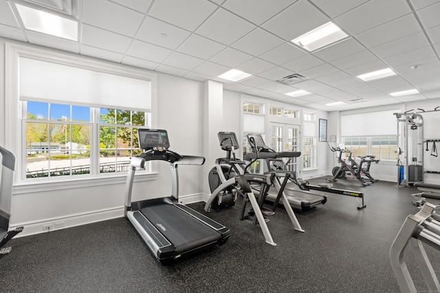 exercise room with baseboards, visible vents, and a drop ceiling