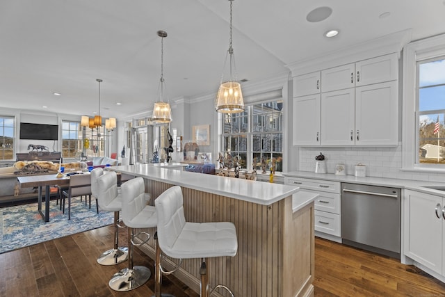 kitchen with a kitchen bar, white cabinets, light countertops, and stainless steel dishwasher