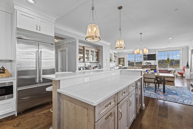 kitchen featuring built in refrigerator, light brown cabinets, open floor plan, and hanging light fixtures