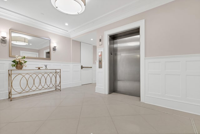 corridor featuring elevator, light tile patterned floors, a decorative wall, crown molding, and a wainscoted wall