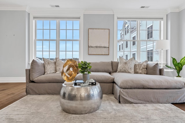 living room with visible vents, baseboards, ornamental molding, and wood finished floors