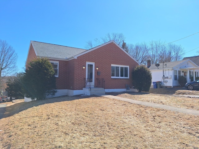 ranch-style house featuring brick siding and roof with shingles