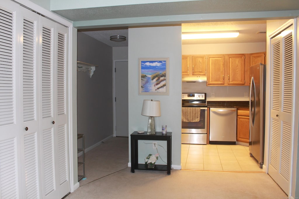 kitchen featuring light colored carpet, light brown cabinetry, and appliances with stainless steel finishes