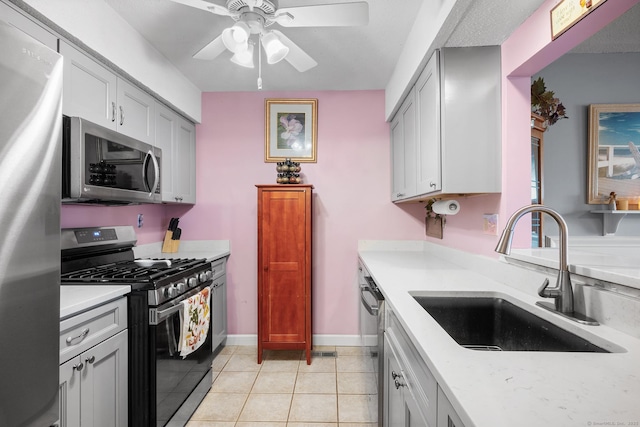 kitchen featuring gray cabinetry, sink, ceiling fan, light tile patterned floors, and stainless steel appliances