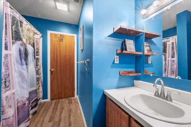 bathroom with hardwood / wood-style floors, vanity, a textured ceiling, and walk in shower