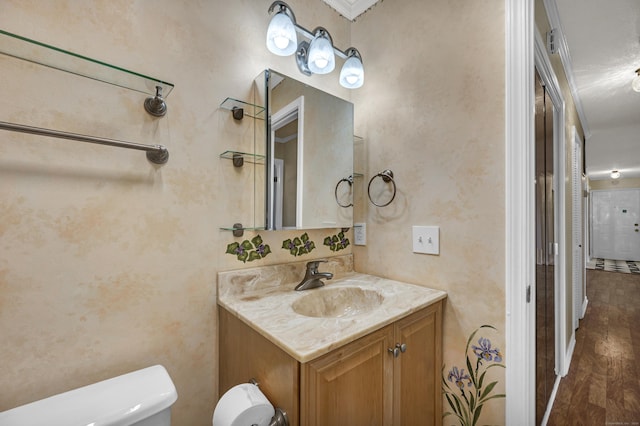 bathroom with hardwood / wood-style flooring, vanity, toilet, and ornamental molding