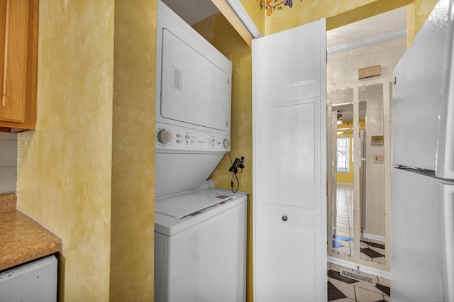 laundry area featuring crown molding and stacked washer and dryer