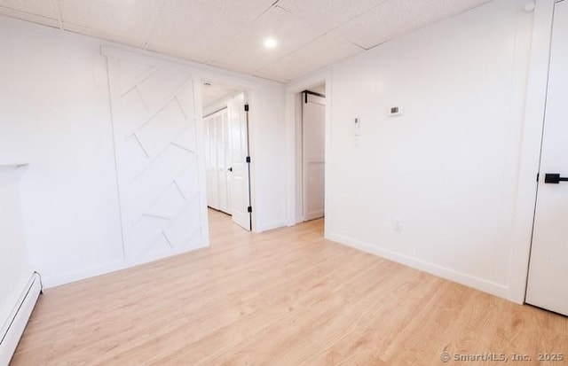 empty room featuring baseboard heating and light wood-type flooring