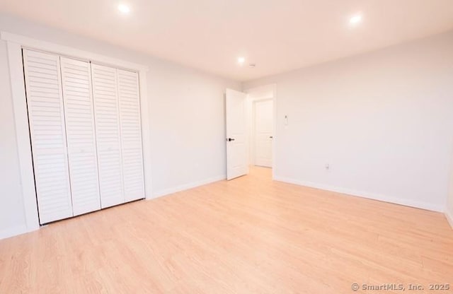 unfurnished bedroom with light wood-type flooring and a closet