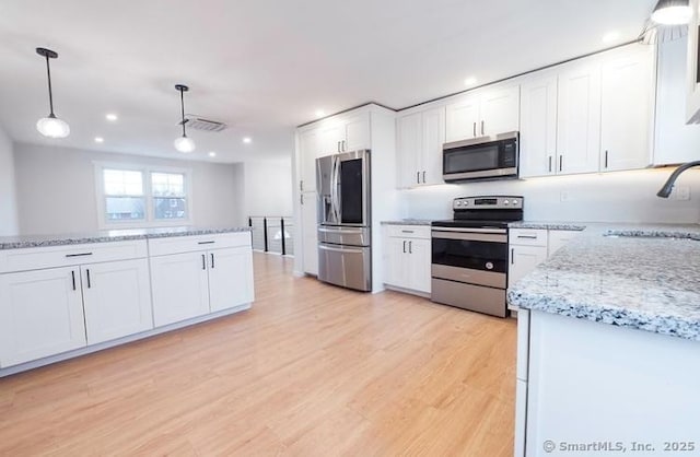 kitchen with sink, appliances with stainless steel finishes, white cabinets, and decorative light fixtures