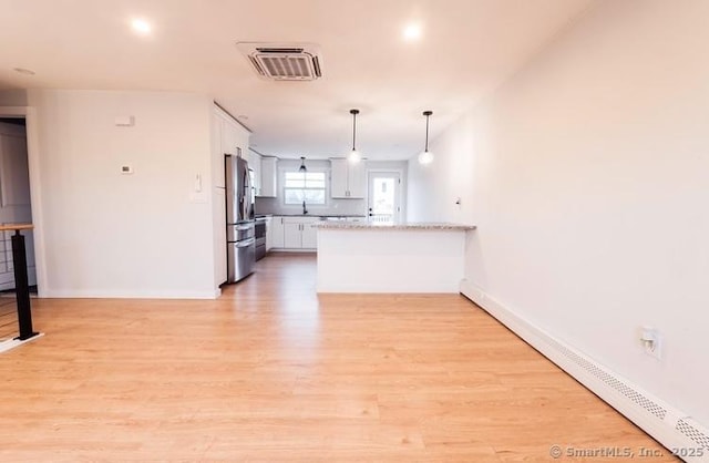 kitchen featuring white cabinets, baseboard heating, light hardwood / wood-style floors, pendant lighting, and stainless steel refrigerator